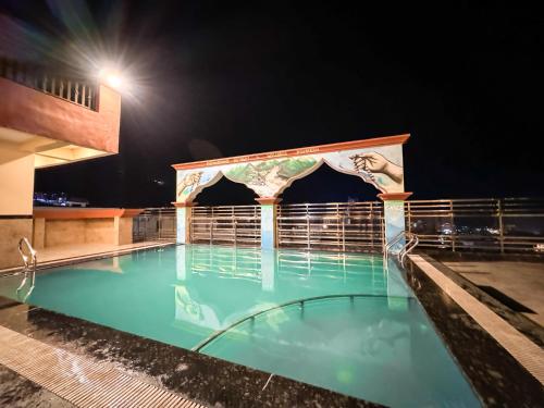 a swimming pool at night with a building at Arogyadham Wellness Retreat in Rishīkesh