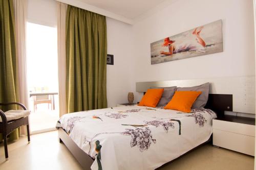 1 dormitorio con 1 cama grande con almohadas de color naranja en appartement gelegen aan de golfbaan op La Quinta Benahavis Marbella, en Benahavís