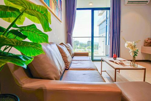 a living room with a leather couch and a plant at Classy Home - CSJ Tower Vũng Tàu, Luxury, Sky-Sea View and Walk-To-Beach in Xã Thang Tam