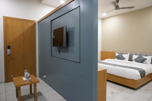 a bedroom with a bed and a tv on a wall at Hotel Amrut Inn Hospitalities in Somnath
