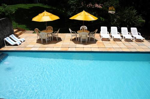a group of chairs and umbrellas next to a pool at Hotel Daniela in Penedo