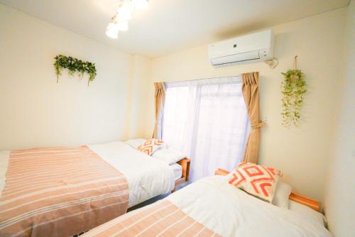 a room with two beds and a window with plants at -Hideaway Miyakojima- 都島駅徒歩3分梅田10分長期滞在OK都会の静かな隠れ家 in Osaka