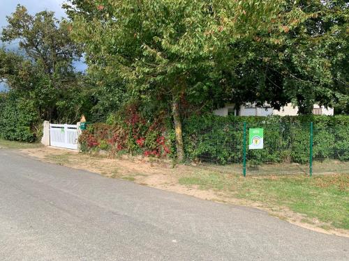 une clôture avec un arbre et un panneau sur le côté d'une rue dans l'établissement Chez Suzanne, à Saint-Père-sur-Loire