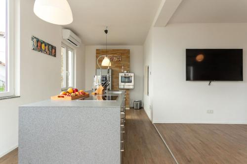 a kitchen with white walls and a counter with fruit on it at Magic Terrace With Lake View in Stazzona