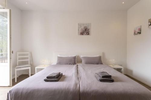 a white bedroom with a large bed with towels on it at Magic Terrace With Lake View in Stazzona