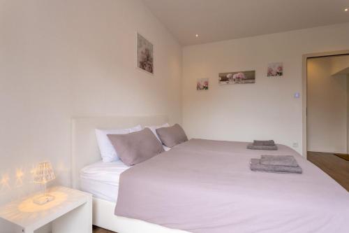a white bedroom with a white bed and a table at Magic Terrace With Lake View in Stazzona