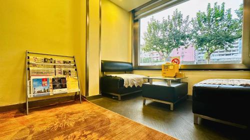 a room with a chair and a table and a window at Shanghai Zhongan Hotel Xizang North Road Subway Station Branch in Shanghai