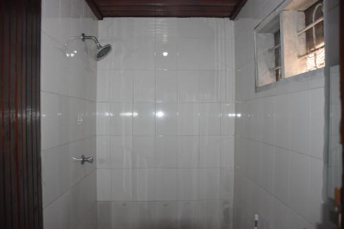 een badkamer met een douche met witte tegels bij Kituri Hostel in Dar es Salaam