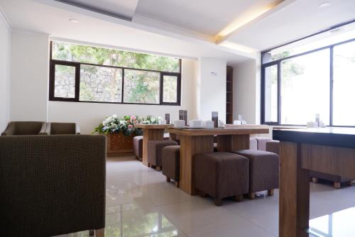 a waiting room with tables and chairs and windows at Point C Hotel in Bandung