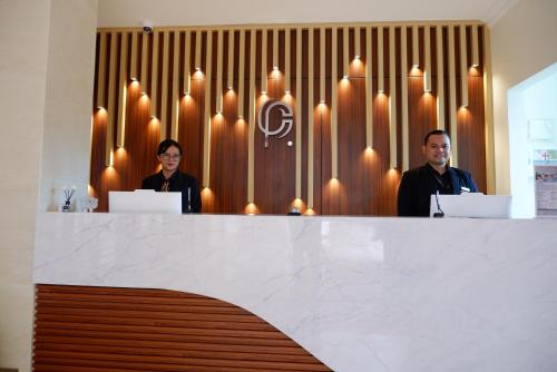 two people standing behind a counter in a room with aitating at Point C Hotel in Bandung