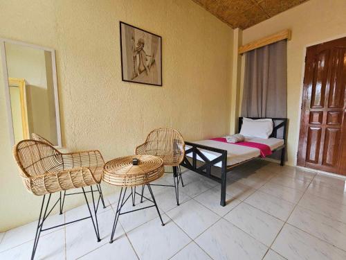 a room with a bed and chairs and a table at Acacia Sunset Village Inn in Dauis