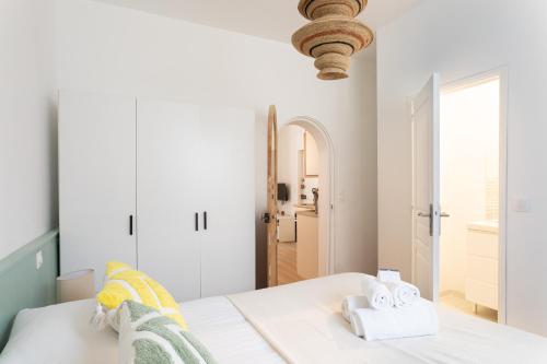 une chambre blanche avec un lit avec des serviettes dessus dans l'établissement Terra Rosa - Apt à 5min de la plage, à Dinard