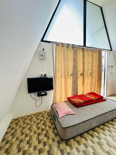 a bed in a room with a large window at TULDA BAMBUSA RESORT in Kāziranga