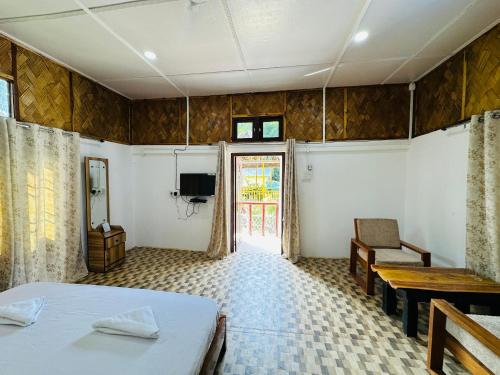 Un dormitorio con una cama y una mesa y una ventana. en TULDA BAMBUSA RESORT, en Kāziranga