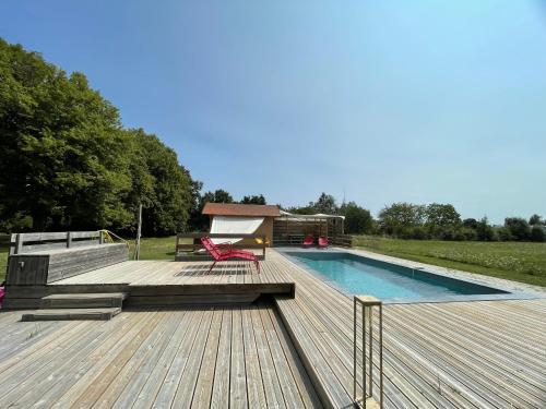 une terrasse avec une piscine et une terrasse en bois dans l'établissement Château des Edelins, à Bayet