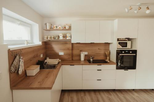a white kitchen with white cabinets and a sink at Barátúri Barátok Vendégház in Barátúr