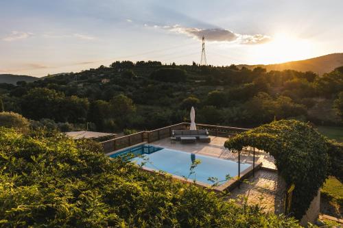 a swimming pool in the middle of a hill with the sunset at Le Cerqueta in Castel Madama