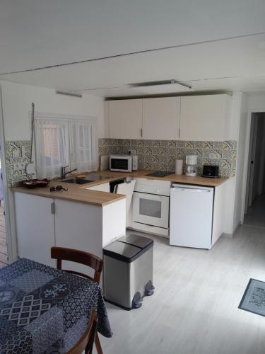 une cuisine avec des armoires blanches et une table et des chaises dans l'établissement Un petit havre de paix, à La Rouviere