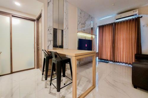 a kitchen with a wooden table and black chairs at Spacious and Homey 2BR at Sky House BSD Apartment By Travelio in Tangerang