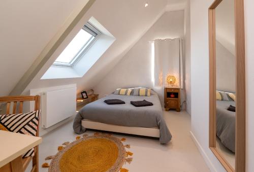 a attic bedroom with a bed and a mirror at Les Palissades - La mer du bon côté in Saint-Pierre-Quiberon