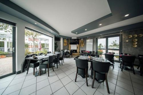 une salle à manger avec tables, chaises et fenêtres dans l'établissement Brit Hotel La Bonne Etape, à Évreux