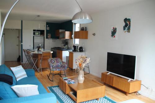 un salon avec un canapé bleu et une télévision dans l'établissement Nid Douillet à 15 min à pied du Lac, à Annecy