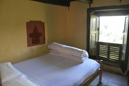 Un dormitorio con una cama en una habitación con ventana. en Newa Guest House Bandipur, en Bandipur
