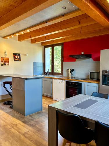 une cuisine aux murs rouges et une table avec des chaises dans l'établissement Chez Fred 201 - Parking Wifi - CLG Savoie, à Chevillard