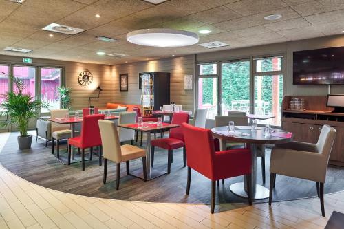 a dining room with tables and chairs and windows at Campanile Villennes-Sur-Seine - Poissy - Hôtel rénové en 2024 in Villennes-sur-Seine
