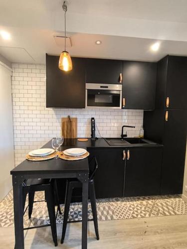 une cuisine avec des armoires noires et une table avec des verres à vin dans l'établissement 2 pieces Perle sur la Place Morny refait à neuf, à Deauville