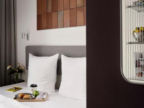 a bed with white pillows and a tray of food on it at Mekano Apartment Hotel in Copenhagen