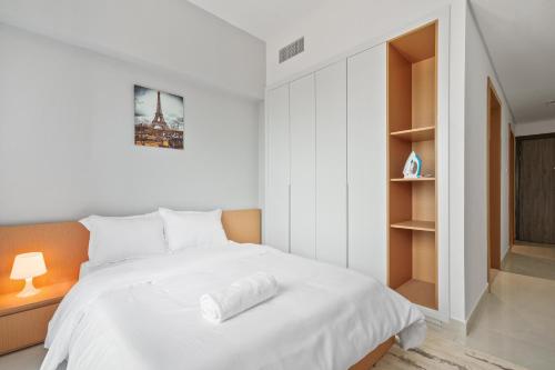a bedroom with a white bed and a book shelf at Stylish Studio Near Dubai Academic City in Dubai