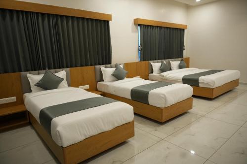 two beds in a hotel room withskirts at Hotel Amrut Inn Hospitalities in Somnath