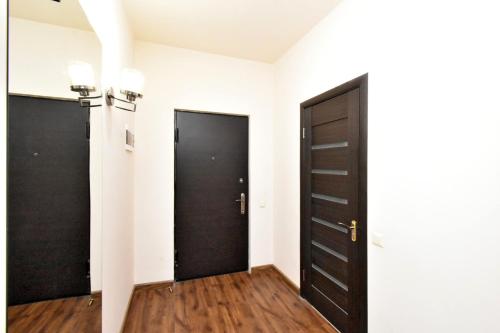 a hallway with two black doors and wooden floors at YARS Apartments in Yerevan