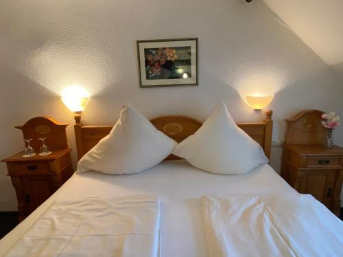 a bed with white sheets and two pillows on it at Hotel Hieronimi in Cochem