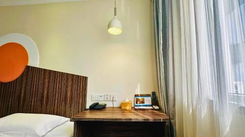 a bedroom with a bed and a desk with a laptop on it at Shanghai Zhongan Hotel Xizang North Road Subway Station Branch in Shanghai