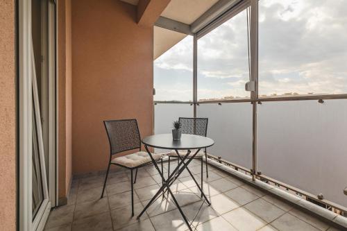 a table and two chairs in a room with a window at Harmony Apartments in Podgorica