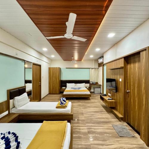 a hotel room with two beds and a ceiling fan at Grand Ambience Resort in Diveagar