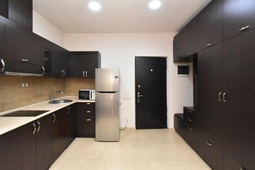 a kitchen with black cabinets and a refrigerator at YARS Apartments in Yerevan