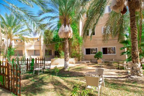 a courtyard with chairs and palm trees in front of a building at Résidence El Arich in Tozeur