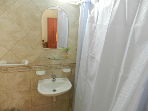 a bathroom with a sink and a white shower curtain at Hotel El Parque in San Clemente del Tuyú