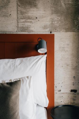 a bed with an orange headboard and a white pillow at GamlaVærket Gjæstgiveri og Tracteringssted in Sandnes