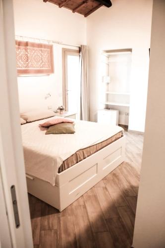 a bedroom with a white bed and a wooden floor at Domu Virginia in Castiadas