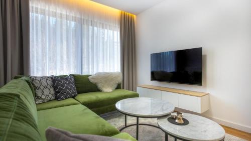 a living room with a green couch and a tv at Aparthotel Phoenix in Bjelašnica