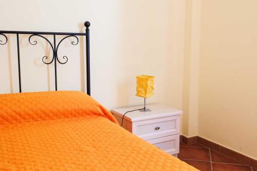 a bed with an orange comforter and a lamp on a night stand at La Terrazza sul Mare in Eraclea Minoa