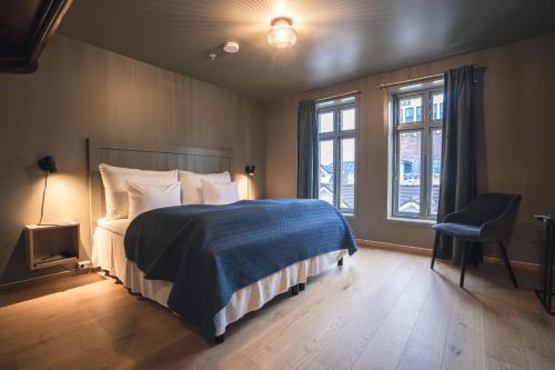 a bedroom with a bed and a chair and windows at GamlaVærket Gjæstgiveri og Tracteringssted in Sandnes