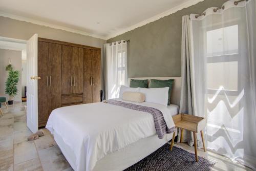 a bedroom with a white bed and a window at Kirrin Cottage in Benoni in Benoni