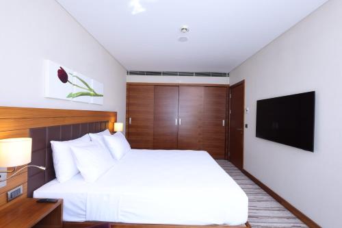a bedroom with a white bed and a flat screen tv at Hilton Garden Inn Konya in Konya