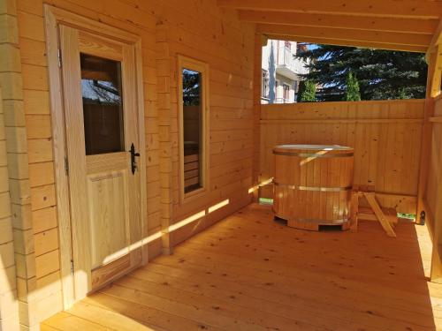a porch of a wooden cabin with a trash can at Willa Hamernik AGROTURYSTYKA in Tylicz