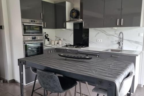 - une cuisine avec une table, 2 chaises et un évier dans l'établissement Maison du Fort Vallières - Bois des forts, à Boomkens